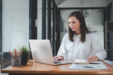 Beautiful woman using laptop while sitting at her working place. Concentrated at work.	