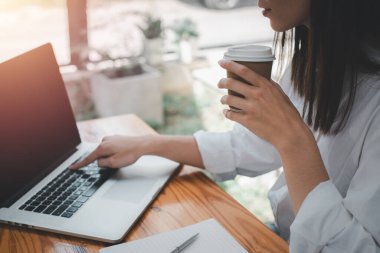 Kapatın, İş kadını el ele tutuşup kahve içiyor ve dizüstü bilgisayar kullanıyor, video, film ya da webinar izliyor, ara veriyor.
