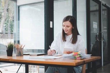 Tamamlanmamış belgelerin aranması ve incelenmesi için dosya yığınlarında çalışan iş kadını yoğun çalışma masasındaki klasörlerde başarıya ulaştı