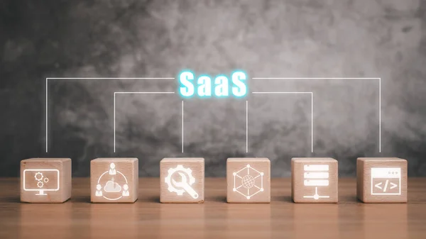 SaaS, software as a service concept, Wooden block on desk with software as a service icon on virtual screen.