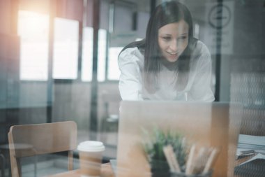 Güzel bir kadın çalıştığı yerde dizüstü bilgisayar kullanıyor. İşine odaklan..