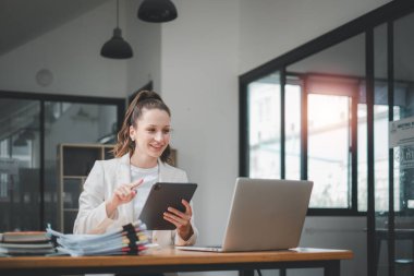 Ofisteki iş raporunu incelemek için tablet ve laptop kullanan kadın iş kadını