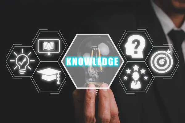 Knowledge concept, Businessman hand holding light bulb with knowledge icon on virtual screen, self learning, knowledge and searching for new ideas. Thinking for new idea.