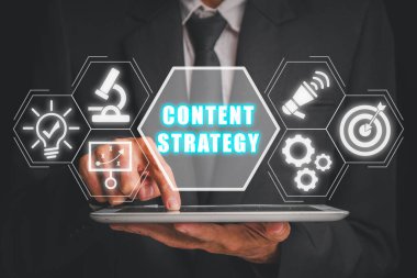 İçerik stratejisi kavramı, iş adamı sanal ekranda içerik strateji simgesiyle dijital tablet kullanıyor.