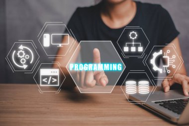 Programlama konsepti, masadaki dizüstü bilgisayarı kullanan ve sanal ekrandaki programlama simgesine dokunan kadın..