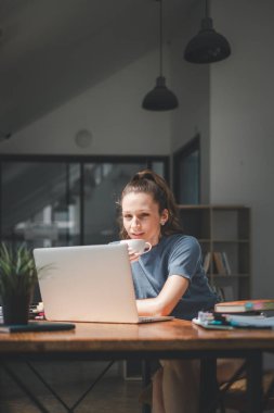 Ciddi bir iş kadını elinde dizüstü bilgisayarla iş raporları hazırlıyor. İş sonuçlarını analiz ediyor. Kadın yöneticiler, veri analizi için çevrimiçi yazılım kullanıyor.