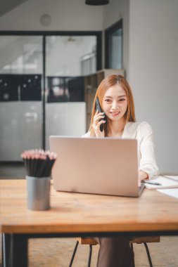 Genç meşgul Asyalı iş kadını yönetici dizüstü bilgisayarda çalışıyor yaratıcı ofiste arama yapıyor profesyonel iş kadını yöneticisi müşteriyle bilgisayar ve iş konsepti kullanarak konuşuyor..