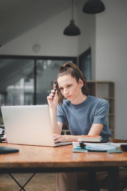 Ciddi meşgul genç iş kadını yöneticisi dizüstü bilgisayara bakıyor finansal dijital piyasa risklerini düşünüyor, yeni kurumsal strateji fikrini düşünüyor, webinar izliyor..