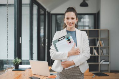 Başarılı iş kadını yaratıcı ofiste dikilip kameraya bakıyor. İş yerinde çalışan kadın girişimci gülümsüyor..