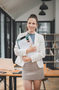 Başarılı iş kadını yaratıcı ofiste dikilip kameraya bakıyor. İş yerinde çalışan kadın girişimci gülümsüyor..