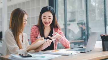 İş ekibi analiz konsepti, iki meşgul bayan meslektaşın ofis masasında coşkuyla bir proje üzerinde tartışması ve çalışması.