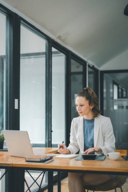İş analitik kavramı, bir iş kadını bilgisayarının başında çalışırken masasında kahve fincanı ve akıllı telefonuyla derinden odaklanır..