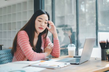 İş analizi konsepti, düşünceli bir iş kadını masasında dizüstü bilgisayarla çalışırken ve modern bir ofiste buzlu kahve içerken düşünceli görünür..