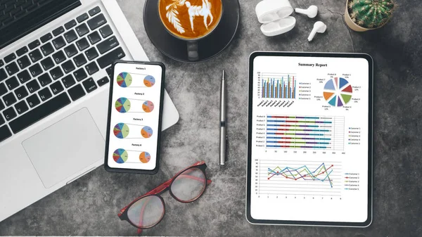 Business analytics concept, An organized desk with a laptop, smartphone, tablet showing colorful pie charts, a pen, glasses, coffee, and earphones, symbolizing a professional business analysis workspace.