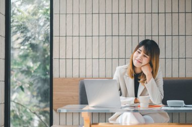 Serbest meslek sahibi bir kadın, modern bir kafede dizüstü bilgisayarıyla çalışır. Masasında kahve ve akıllı telefon bulunur..