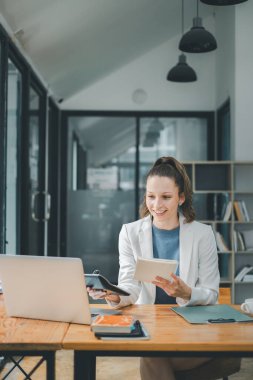 İş analitik kavramı, parlak bir ofis alanında iş kadını hesap makinesi ve dizüstü bilgisayarla birden fazla iş yapıyor, modern verimliliği simgeliyor..