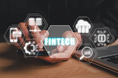 Fintech konsepti, ofis masasında akıllı telefon kullanan iş kadını ve sanal ekranda fintech simgesi.