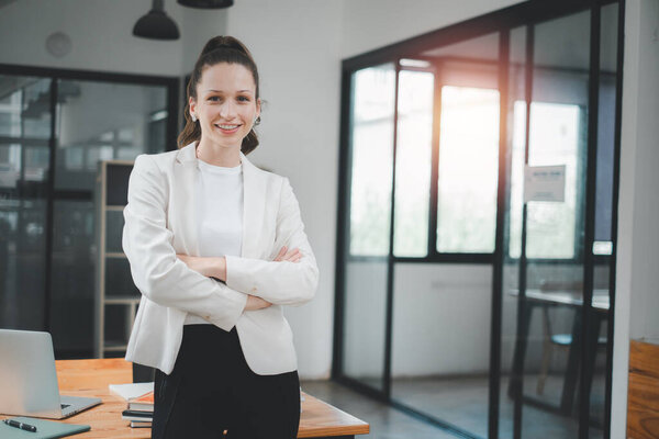 Professional young businesswoman with a confident smile standing in a bright, contemporary office environment.