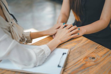 Sağlık hizmeti konsepti, sıcak, davetkar bir muayenehanede hastaya rahatlık ve güven sunan bir doktorun elleri gösterilir..