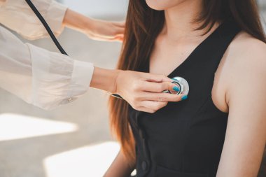 Bir sağlık uzmanı, güneşli ve çağdaş ofis ortamında bir çalışana rutin bir steteskop kontrolü yapar..