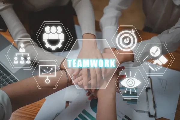 Teamwork concept, Positive diverse business team putting their hands on top of each other with teamwork icon on virtual screen.