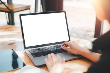 Boş ekranlı bir dizüstü bilgisayarda çalışmak, güneşli bir ofis alanında modelleme için ideal, potansiyeli vurgulamak ve odaklanmak..