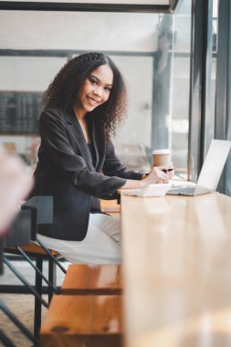 Kafe masasında dizüstü bilgisayarla çalışan profesyonel bir genç kadın..