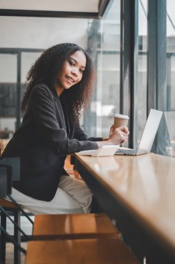 Kafe masasında dizüstü bilgisayarla çalışan profesyonel bir genç kadın..