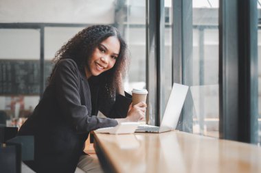 Kafe masasında dizüstü bilgisayarla çalışan profesyonel bir genç kadın..
