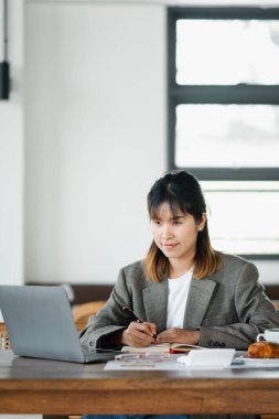 Çalışkan bir iş kadını dizüstü bilgisayarının yanındaki iyi organize edilmiş bir iş ortamında not alıyor..