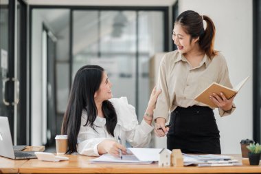 İki nişanlı bayan meslektaşımız bir ofis masasında not defteri ve kağıtlarla açık yüreklilikle tartışıyorlar..
