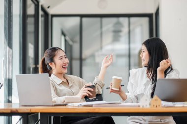 Ofis masasında dizüstü bilgisayarları açık kahve molası veren iki neşeli kadın heyecanlı bir sohbete girişiyor..