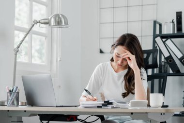 Odaklanmış bir kadın, evrak işlerini titizlikle halleder, organize bir ofis masasındaki görevlerini yönetir..