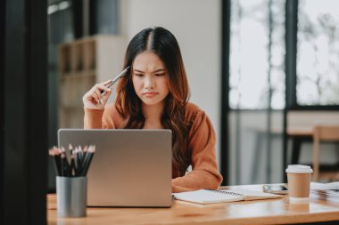 Modern ofis ortamında bilgisayarındaki verileri analiz eden, çatık kaşlı, konsantre genç bir kadın..