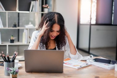 Elleri saçında, dizüstü bilgisayarına bakan stresli bir iş kadını zor bir görevin baskısını hissediyor..