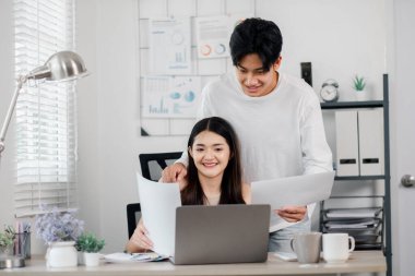 Neşeli çift, parlak bir ev ofisinde dizüstü bilgisayarla kağıtları gözden geçirip tartışıyorlar..