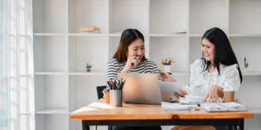 Modern bir ofiste bir iş projesinde birlikte çalışırken iki bayan meslektaşı aynı anda neşeli bir anı paylaşıyor..