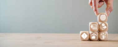 Akıl hocalığı konsepti, hedefleri, koçluğu, güveni, olayı, motivasyonu ve sanal ekranda başarı ikonu olan ahşap bloğu masada tutmak.