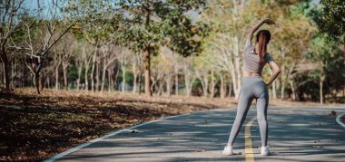 Bir kadın yolda geriniyor. Gri pantolon ve gri bir gömlek giyiyor. Yol boş ve etrafta başka kimse yok.