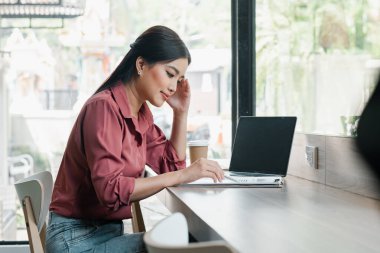 Bir kadın dizüstü bilgisayarı ve not defteriyle masada oturuyor. O, pembe bir gömlek giyiyor ve başını elinin üzerinde dinlendiriyor. Sahne onun çalıştığını ya da çalıştığını gösteriyor.
