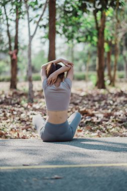 Kadın dışarıda yoga yapıyor, huzurlu bir park ortamında geriniyor, sağlıklı bir yaşam tarzını ve farkındalığı kucaklıyor..