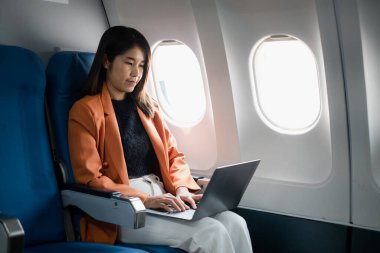 Uçuş sırasında dizüstü bilgisayarda çalışan profesyonel bir kadın iş seyahatleri ve ulaşım sırasında üretkenlik sergiliyor..
