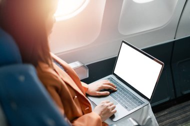 İş kadını uçakta dizüstü bilgisayar kullanıyor, uçuş verimliliği ve modern iş seyahatleri sergiliyor..