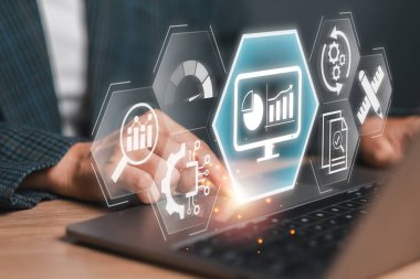 Veri analizlerini, performans takibini ve konseptleri temsil eden dijital simgeleri olan bir dizüstü bilgisayar kullanan bir iş adamı..