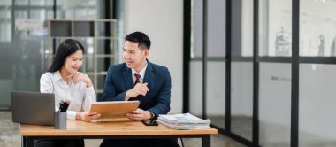 Modern ofis ortamında profesyonel iş arkadaşları, bir iş toplantısında, belgeleri tartışıyorlar ve teknolojiyi kullanıyorlar..