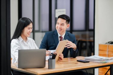 Modern ofis ortamında iki iş adamı, belgeleri incelerken bir tartışma içindeler ve bir dizüstü bilgisayar üzerinde çalışıyorlar..