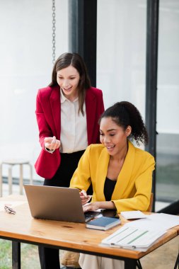 Çağdaş ofis ortamında dizüstü bilgisayarda birlikte çalışan iki profesyonel kadın takım çalışması ve işbirliği sergiliyor..