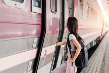 Sırt çantası ve kamerası olan genç bir kadın gün doğarken tren istasyonunda trene biniyor. Yolculuk ve maceraya hazır..