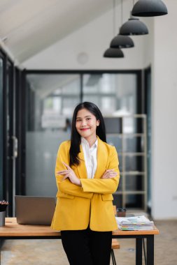 Sarı ceketli profesyonel bir kadın modern ofis ortamında kendine güveniyor liderlik ve başarı sergiliyor..