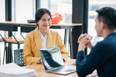 İki meslektaş, modern bir ofiste profesyonel bir iş görüşmesinde doğal ışık altında dizüstü bilgisayarla iş konuşuyorlar..